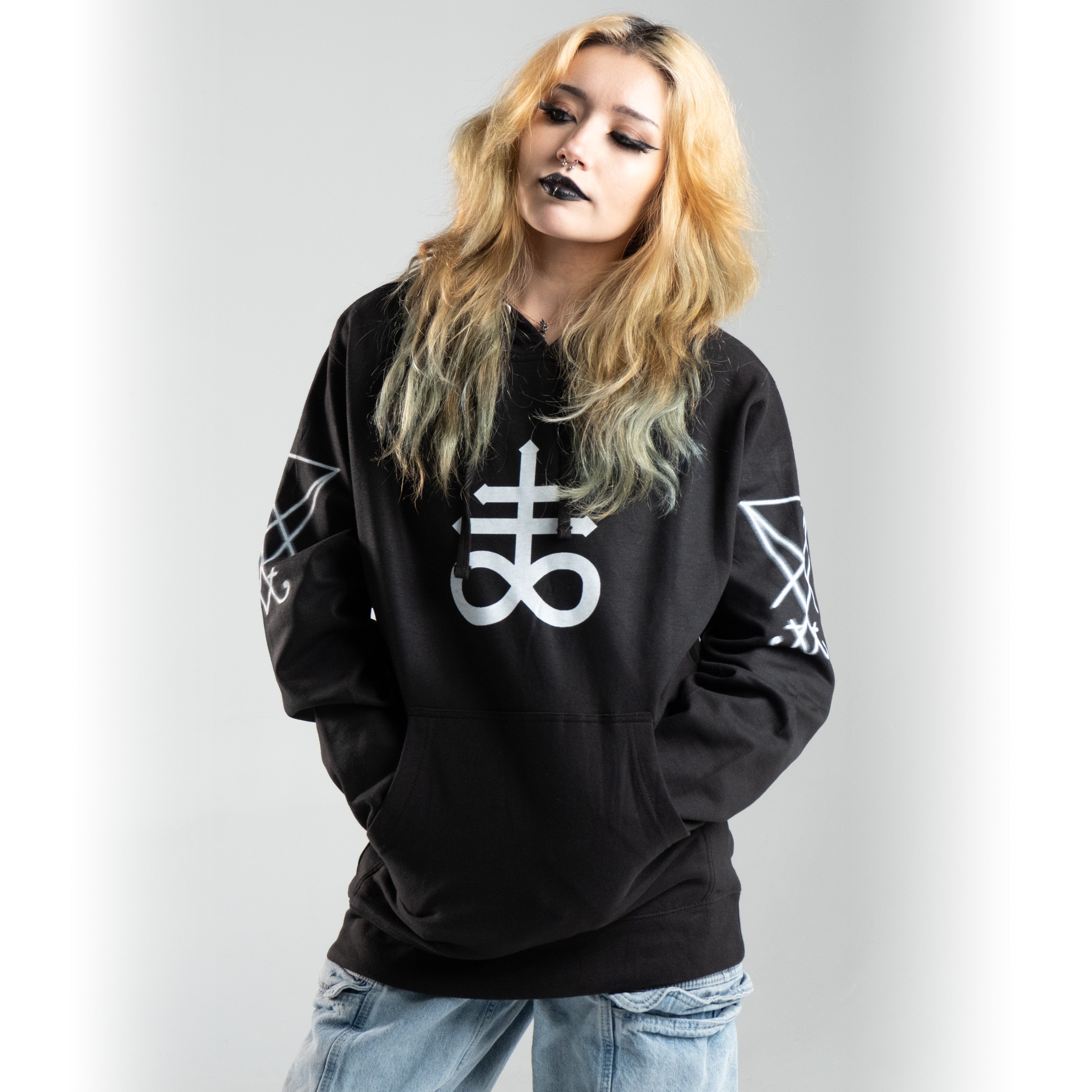Person wearing Leviathan Cross Hoodie in black with white alchemy symbols, 100% cotton, showcasing unique and vibrant design.