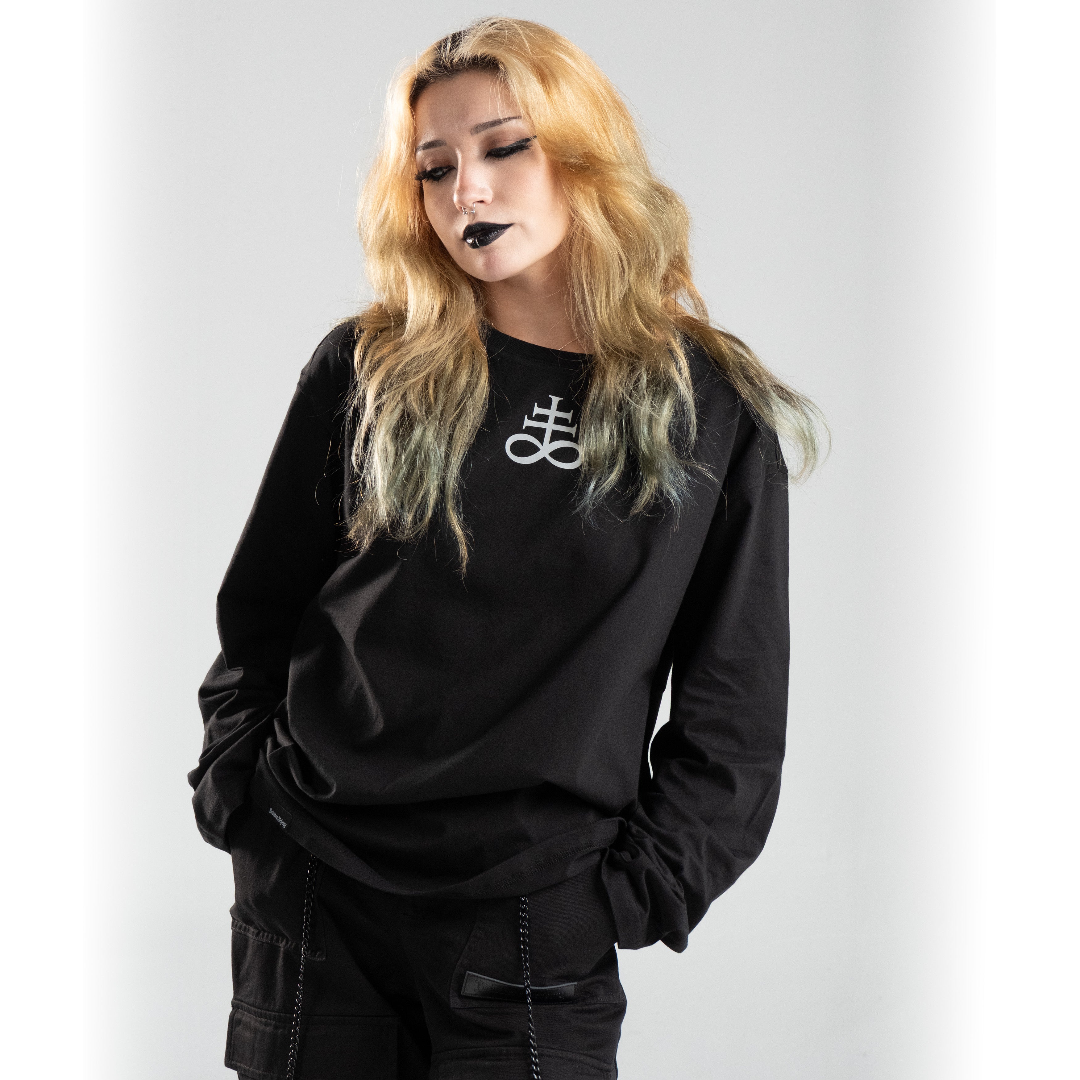 Person wearing Nocturne Sigil long sleeve shirt in black, featuring a bold white symbol, embodying an edgy and alternative style.