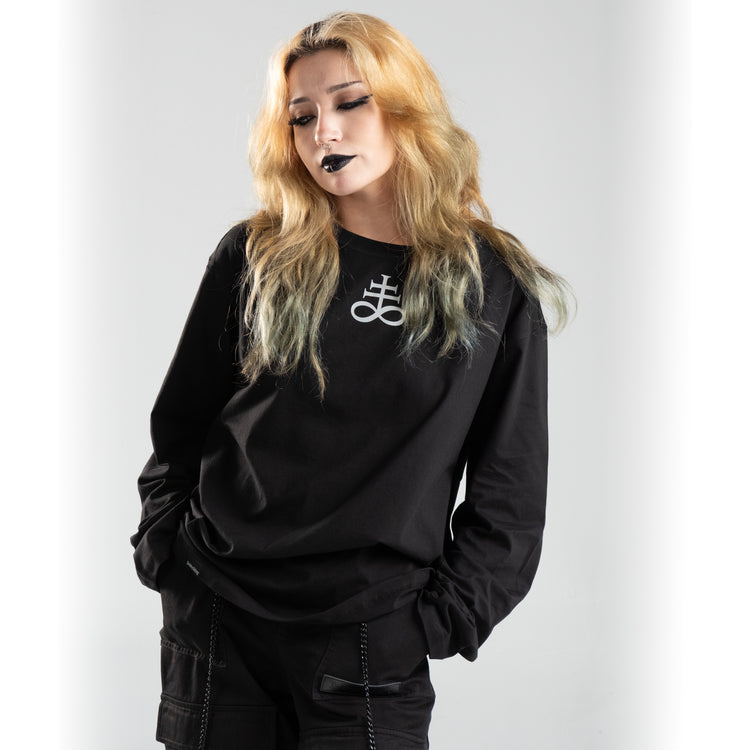 Person wearing Nocturne Sigil long sleeve shirt in black, featuring a bold white symbol, embodying an edgy and alternative style.