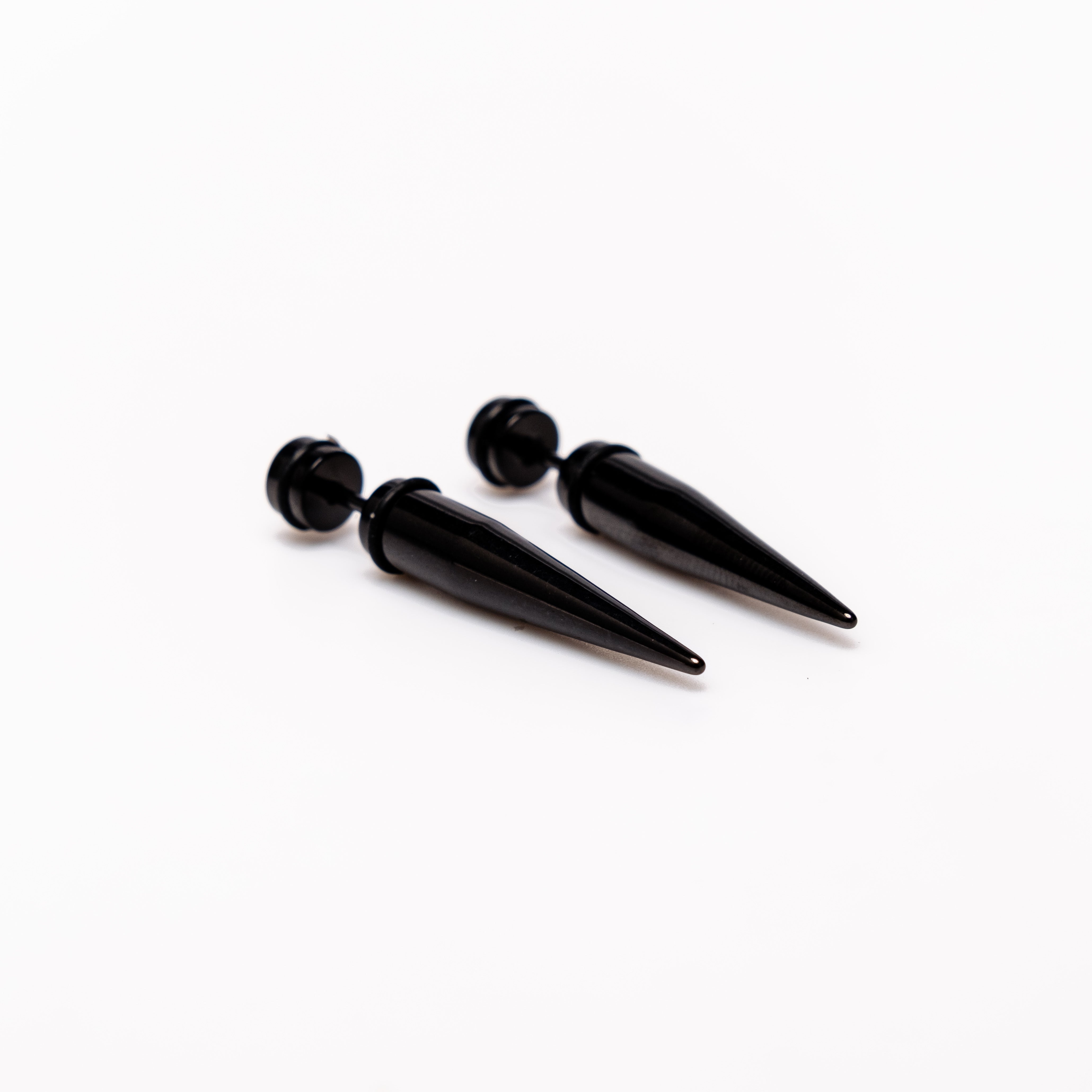 Black Spike - Earrings Dare to make a statement with our Black Spike Earrings. Crafted from high-quality alloy and painted in sleek black, these earrings are designed to mimic the look of actual gauges, adding a bold edge to your style. With a length of 1